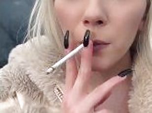 A glamour teen is smoking and spitting loogies on the ground making big spit puddle