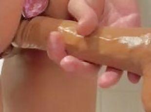 Petite girl with butt plug fucking a wall mounted dildo in the bathroom while standing - ABabyOF